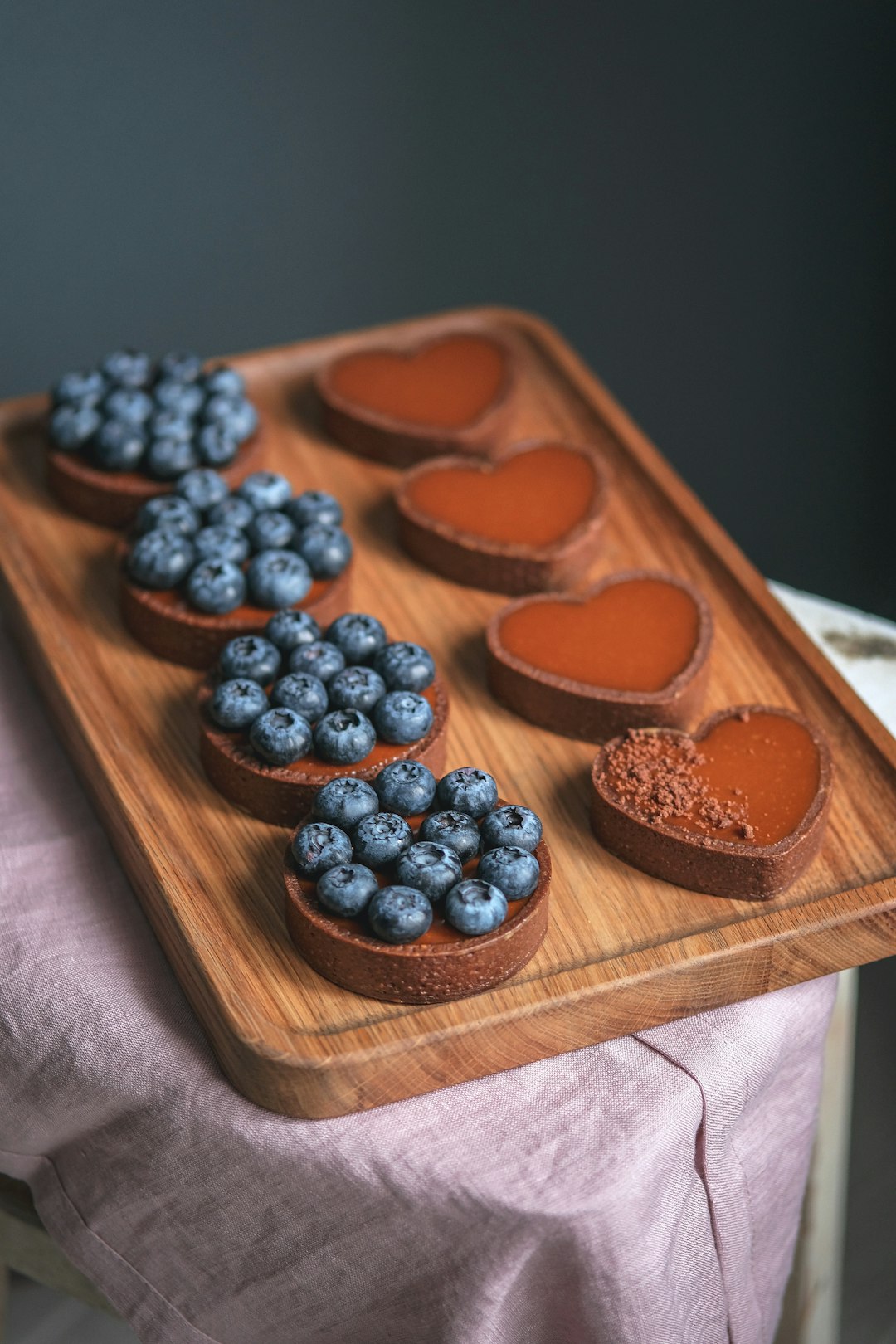 a wooden tray topped with heart shaped cakes and blueberries