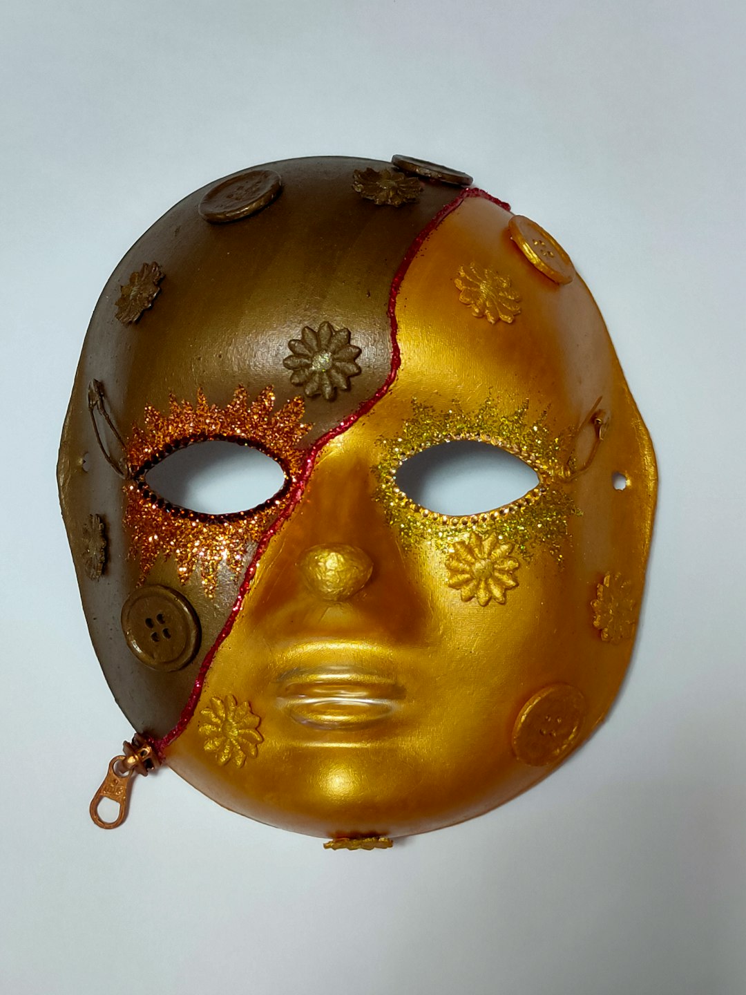 A gold mask hanging from a wall